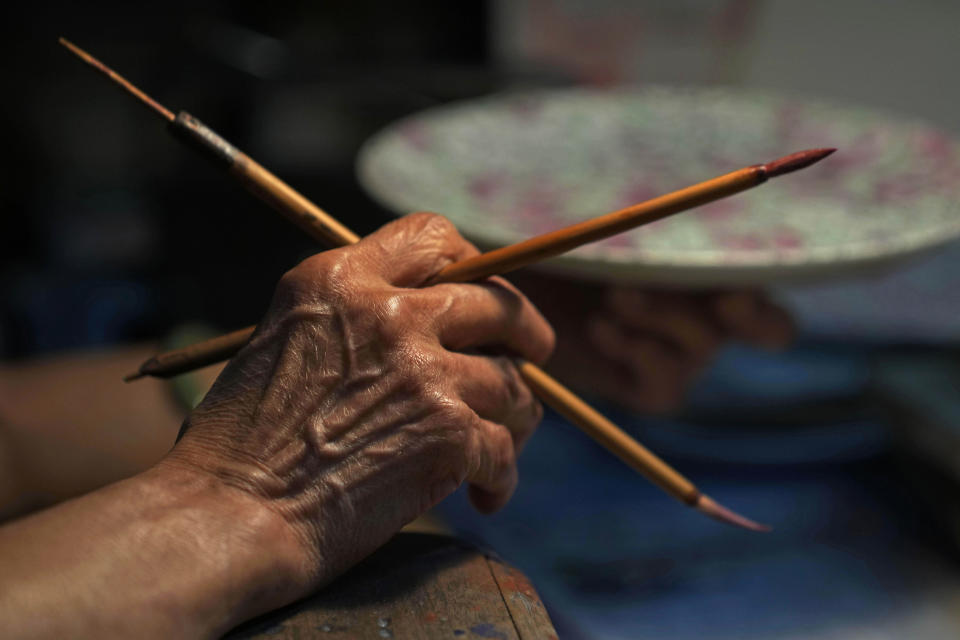 A staff member works at the Yuet Tung China Works, Hong Kong's last hand-painted porcelain factory, in Hong Kong, Wednesday, June 8, 2022. The traditional technique of painting “guangcai,” or Canton porcelain is a fading art in this modern metropolis, as fewer young people are willing to put in the time and effort required to master the craft or to work at the factory full-time.(AP Photo/Kin Cheung)