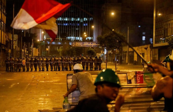 FOTO DE ARCHIVO. Los manifestantes se cubren con un escudo improvisado mientras los agentes de policía operan durante una protesta antigubernamental, tras la destitución del expresidente de Perú Pedro Castillo, en Lima, Perú