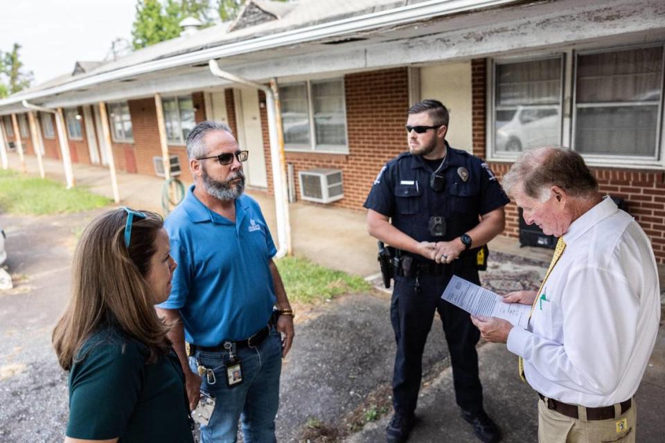 Business owner, Paul Bradley, reviews a warrant in front of law enforcement and code enforcement on his commercial property in Charlotte, N.C., on Wednesday, September 20, 2023. Paul Bradley is in a dispute with code enforcement over him allowing homeless people to camp on his commercial property