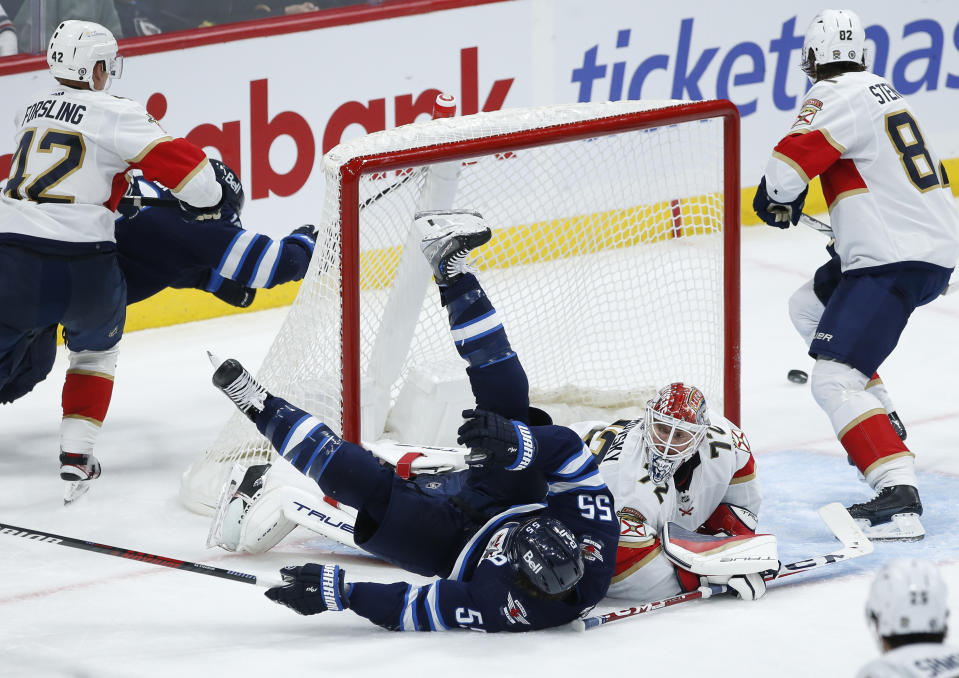 Winnipeg Jets' Mark Scheifele (55) crashes into Florida Panthers goaltender Sergei Bobrovsky (72) as Panthers' Kevin Stenlund (82) defends during third-period NHL hockey game action in Winnipeg, Manitoba, Saturday, Oct. 14, 2023. (John Woods/The Canadian Press via AP)