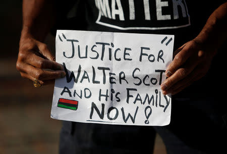 Scott family supporter Dmitri Ford of Charleston, holds a sign outside the federal court building during the sentencing hearing for Michael Slager in Charleston, South Carolina, U.S. December 4, 2017. REUTERS/Randall Hill