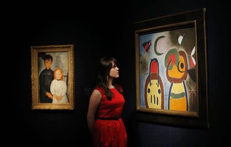 A member of staff poses with "L'oiseau au plumage deploye vole vers l'arbre argentee" (R) by Joan Miro at Christie's auction house in London, January 30, 2015. REUTERS/Suzanne Plunkett