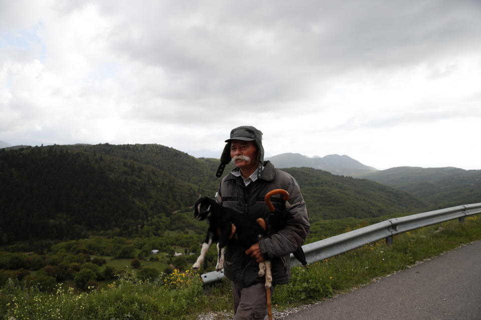 In this Tuesday, May 14, 2019, photo an elderly man holds a goat kid in Kerasohori village at Evrytania region, in central Greece. The area, a winding, three-hour drive from Athens, has the oldest population in the whole European Union, 54.3 on average. (AP Photo/Thanassis Stavrakis)