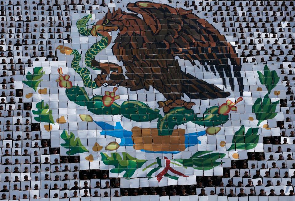 Hundreds of military troops hold cards making a mosaic depiction of the Mexican coat of arms in Mexico City, Wednesday, Sept. 14, 2016.