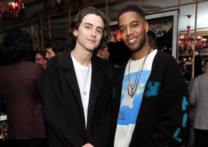 Closeup of Timothée and Kid Cudi smiling for a photo together in a room full of people