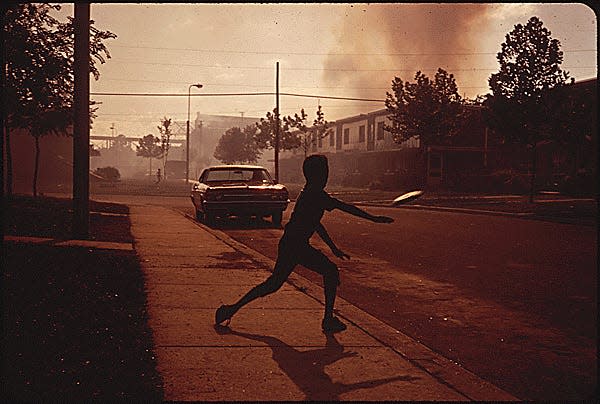 TOSSING A FRISBEE ON A SMOKE-FILLED STREET IN NORTH BIRMINGHAM, MOST HEAVILY POLLUTED AREA OF THE CITY