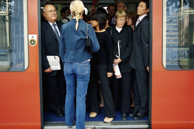 Rear View of a Blonde Woman Trying to Board a Crowded Train