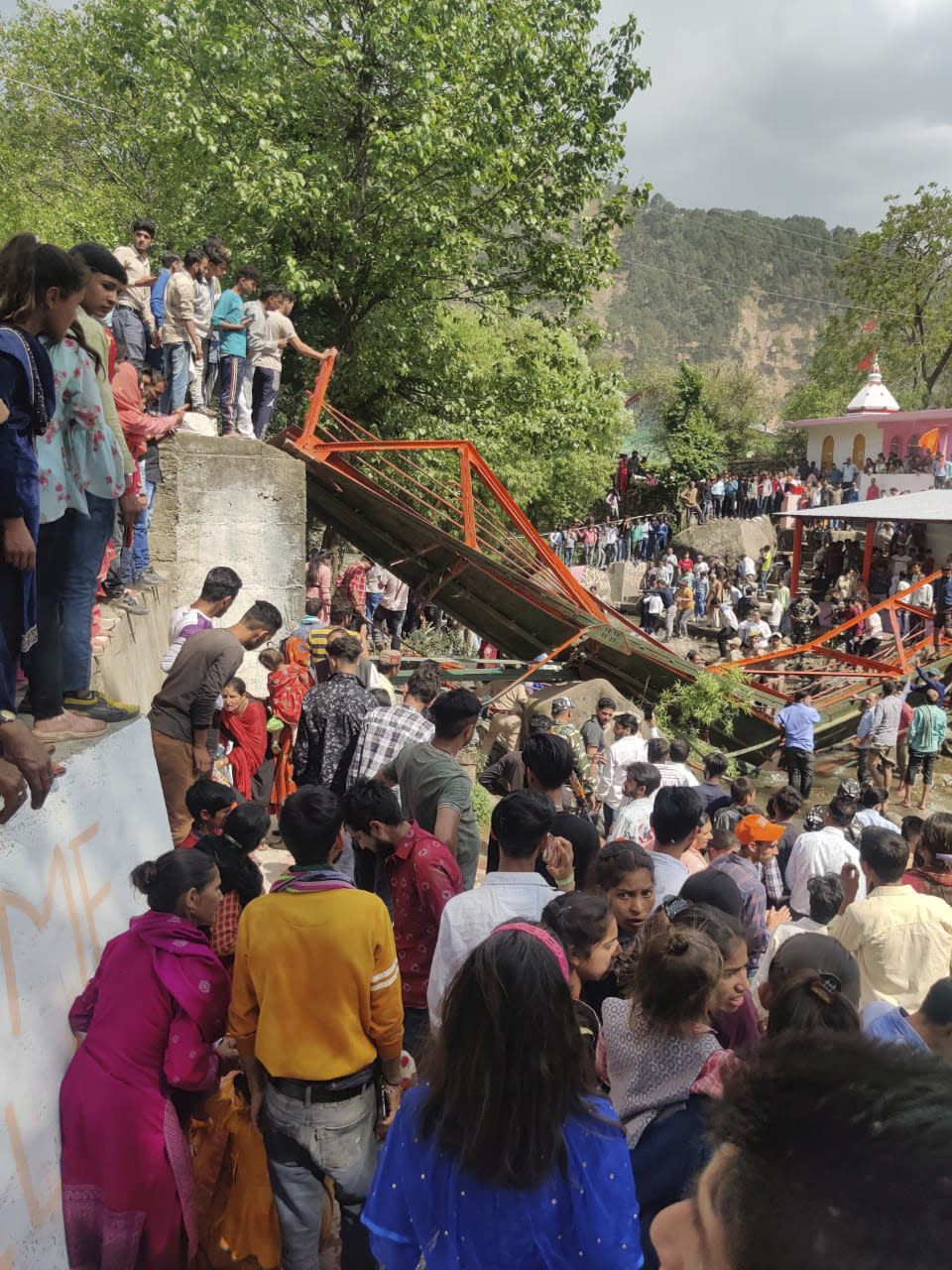 People crowd near a steel footbridge which collapsed during the Baisakhi fair in Udhampur, near Jammu, India, Friday, April, 14, 2023. Indian officials have reported that at least 62 people were injured when a steel footbridge collapsed during the Baisakhi fair in Udhampur's Bain village. (AP Photo)