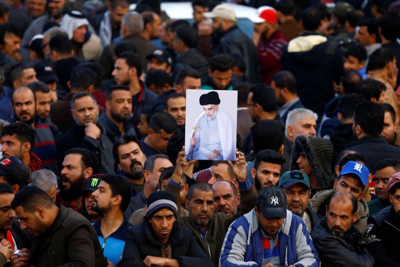 Supporters of Iraqi Shi'ite cleric Moqtada al-Sadr carry his picture near his home, after it was attacked, in the holy city of Najaf