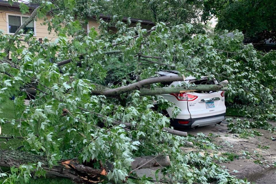 In this image provided by Kathy Long VanVoorhis, a large tree rests on top of a car, Thursday, July 9, 2020, in Fergus Falls, Minn., following a severe storm the day before. (Kathy Long VanVoorhis via AP)