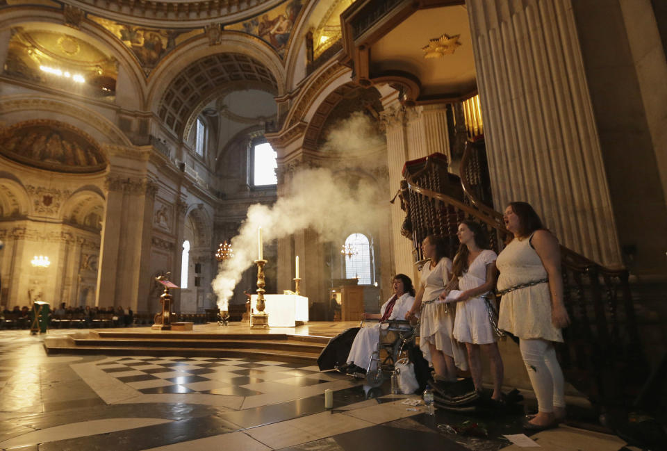 Four women activists of the Occupy movement protest chained to the pulpit inside St Paul's Cathedral as preparations for evensong take place in London, Sunday, Oct. 14, 2012. Several supporters of the anti-corporate Occupy movement chained themselves to the pulpit of St. Paul's Cathedral during a service on Sunday in an action marking the anniversary of its now-dismantled protest camp outside the London landmark. (AP Photo/Alastair Grant)