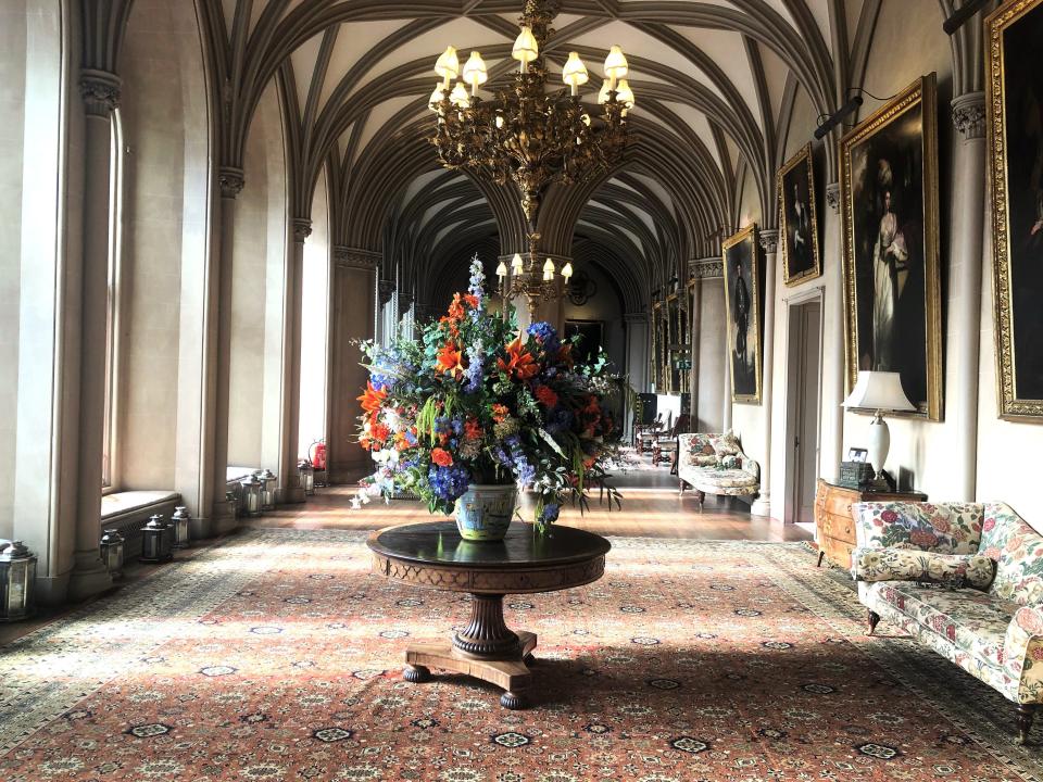 A long hallway with arched ceiling and a table with a floral centerpiece.