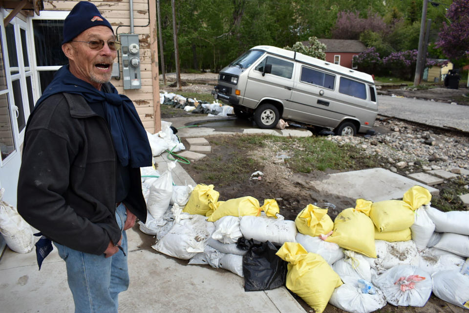 Ken Ebel is seen in front of his flood-damaged house and yard, Tuesday, June 14, 2022, in Red Lodge, Mont. Ebel says sandbags placed by volunteers likely spared his property from further damage. (AP Photo/Matthew Brown)