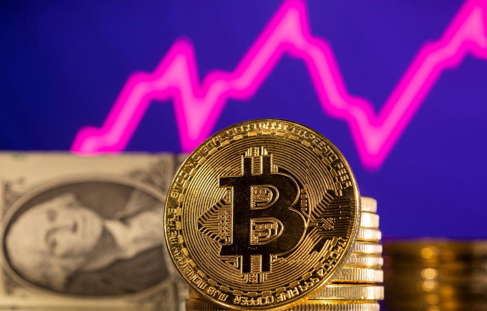 A representations of cryptocurrency Bitcoin is seen in front of a stock graph and U.S. dollar in this illustration taken, January 24, 2022. REUTERS/Dado Ruvic/Illustration