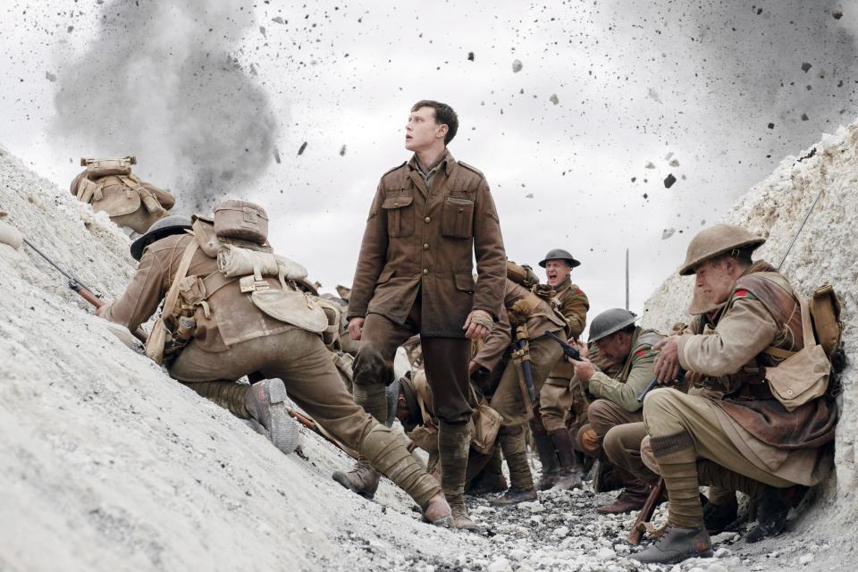 Lance Corporal William Schofield standing in a trench in his uniform with other uniformed soldiers around him