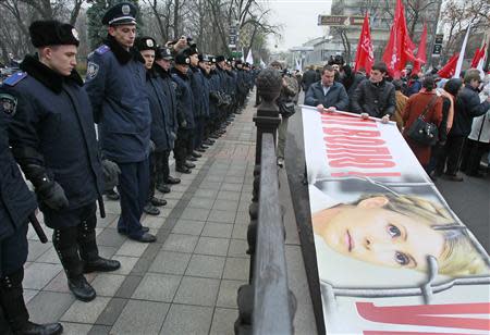 Police stand guard as opposition supporters roll a banner with the portrait of jailed former prime minister Yulia Tymoshenko after a rally in front of the Parliament building in Kiev November 13, 2013. REUTERS/Gleb Garanich