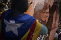 A man holds printed image of former Catalan leader Carles Puigdemont as people take part in a protest outside the Italian consulate in support of Puigdemont in Barcelona, Spain, Friday, Sept. 24, 2021. Puigdemont, who fled Spain after a failed secession bid for the northeastern region in 2017, was detained Thursday in Sardinia, Italy, his lawyer said. Puigdemont, who lives in Belgium and now holds a seat in the European Parliament, has been fighting extradition to Spain, which accused him and other Catalan independence leaders of sedition. (AP Photo/Joan Mateu)