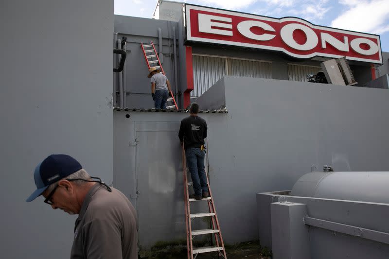 Men work fixing power lines at a store after an earthquake in Guanica