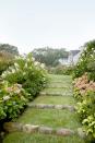 <p>'Tardiva' and 'Annabelle' hydrangeas, 'Diana' Rose of Sharon hibiscus, and Hosta plantaginea frame stone risers, creating the walkway behind this Martha's Vineyard home.</p><p><strong><a href="https://www.countryliving.com/home-design/house-tours/g1440/kitchen-garden-ideas/" rel="nofollow noopener" target="_blank" data-ylk="slk:Read more about this Martha's Vineyard Home;elm:context_link;itc:0;sec:content-canvas" class="link ">Read more about this Martha's Vineyard Home</a>.</strong></p><p><a class="link " href="https://go.redirectingat.com?id=74968X1596630&url=https%3A%2F%2Fwww.homedepot.com%2Fp%2FPavestone-RockWall-Small-4-in-x-11-75-in-x-6-75-in-Yukon-Concrete-Retaining-Wall-Block-87550%2F204643744&sref=https%3A%2F%2Fwww.countryliving.com%2Fgardening%2Fgarden-tours%2Fg1432%2Flandscaping-ideas%2F" rel="nofollow noopener" target="_blank" data-ylk="slk:SHOP STONE RISERS;elm:context_link;itc:0;sec:content-canvas">SHOP STONE RISERS</a></p>