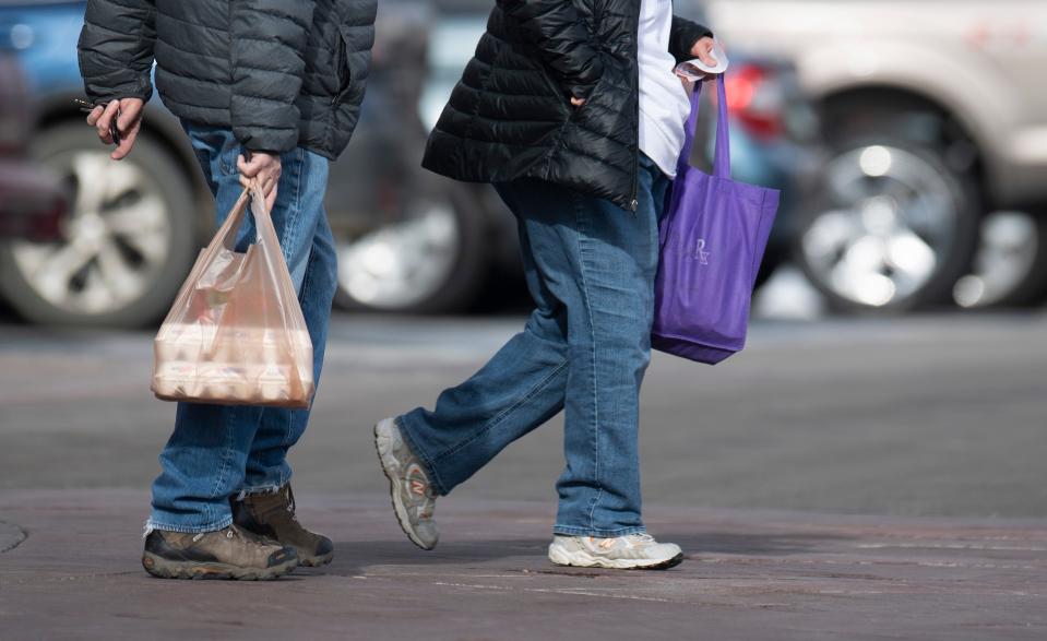 Customers, one carrying a plastic bag and the other carrying a reusable bag, walk out of King Soopers in Fort Collins in this file photo.