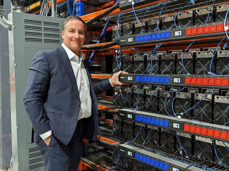 Bitfarms' president Geoff Morphy in front of rows of miners