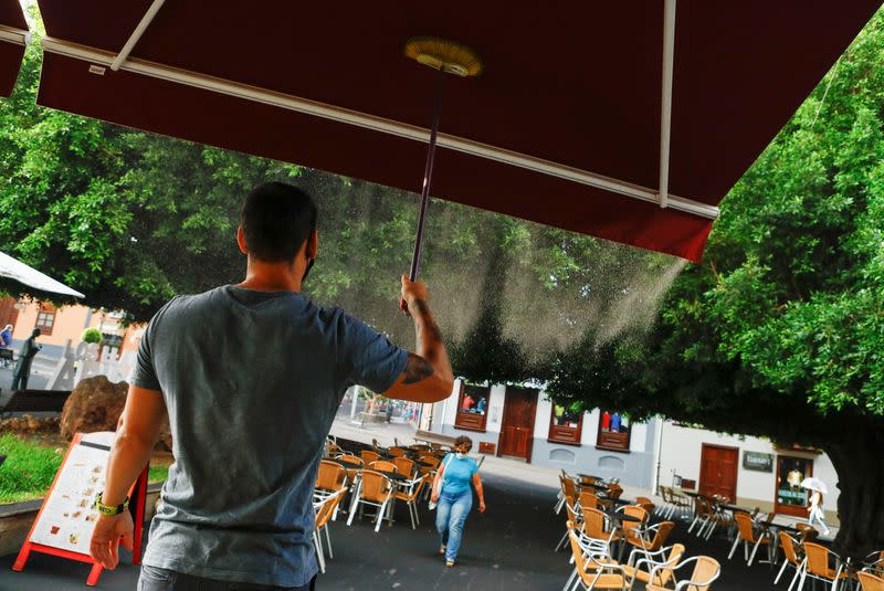 A waiter cleans the ash outside a bar, following the eruption of a volcano on the Canary Island of La Palma