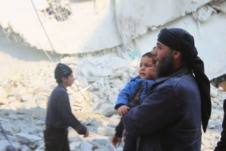 A rescue worker holds an injured boy after what activists said were airstrikes carried out by the Russian air force in Idlib city, Syria December 20, 2015. REUTERS/Ammar Abdullah