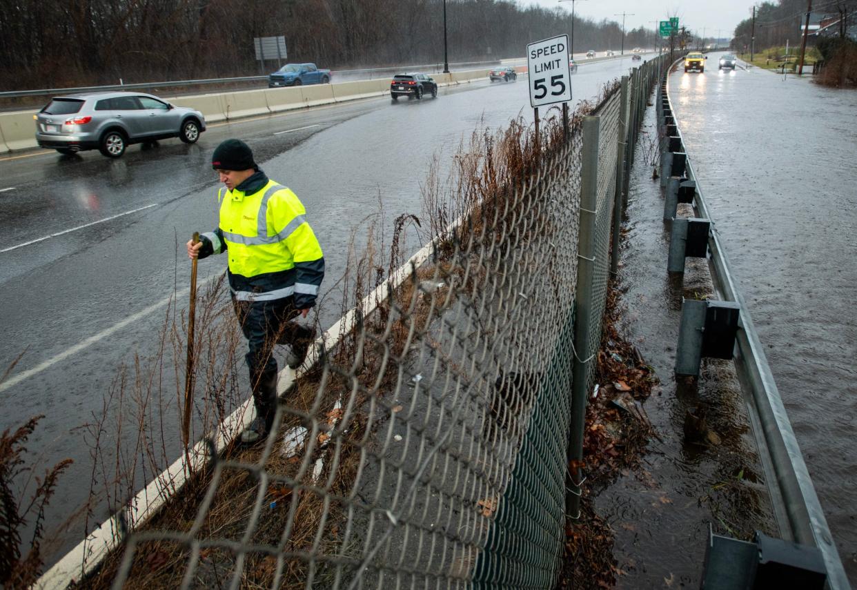 A highway worker clears storm drains on a flooded section of Route 146 and adjacent North Main Street in Millbury Monday.
