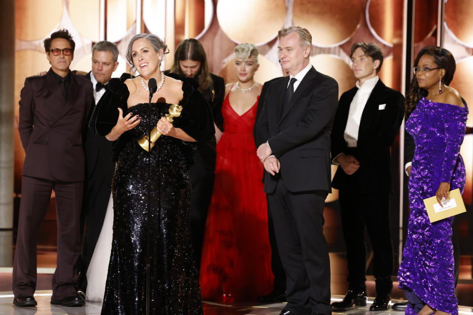 This image released by CBS shows producer Emma Thomas, foreground left, accepting the award for best motion picture drama for "Oppenheimer" as cast and crew members, background from left, Robert Downey Jr., Matt Damon, composer Ludwig Göransson, Florence Pugh, director Christopher Nolan, actor Cillian Murphy and presenter Oprah Winfrey look on during the 81st Annual Golden Globe Awards in Beverly Hills, Calif., on Sunday, Jan. 7, 2024. (Sonja Flemming/CBS via AP)