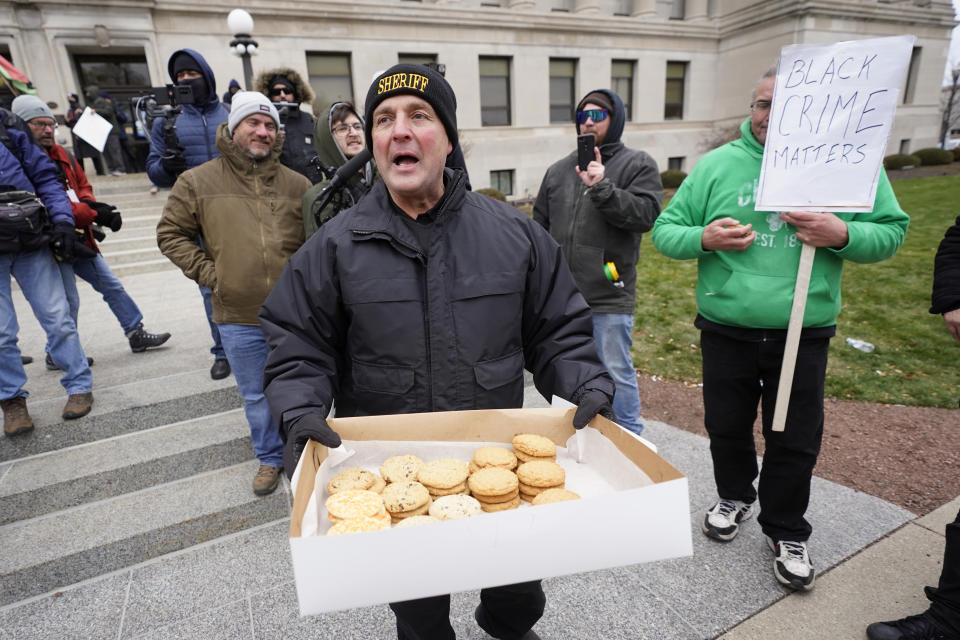 Kenosha County Sheriff David Beth hands out cookies outside the Kenosha County Courthouse, Thursday, Nov. 18, 2021 in Kenosha, Wis., during the Kyle Rittenhouse murder trial. Rittenhouse is accused of killing two people and wounding a third during a protest over police brutality in Kenosha, last year. (AP Photo/Paul Sancya)