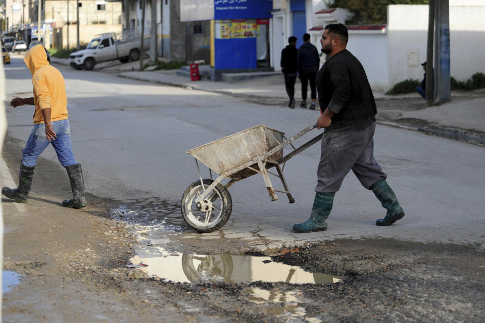 A man pulls a wheelbarrow in a damaged street of La Marsa, outside Tunis, Wednesday, Dec.14, 2022. To outsiders, Tunisia’s legislative elections Saturday, Dec. 17, 2022 look questionable: Many opposition parties are boycotting. A new electoral law makes it harder for women to compete. Foreign media aren’t allowed to talk to candidates. But many voters believe that their country’s decade-old democratic revolution has failed, and welcome their increasingly autocratic president’s political reforms. (AP Photo/Hassene Dridi)