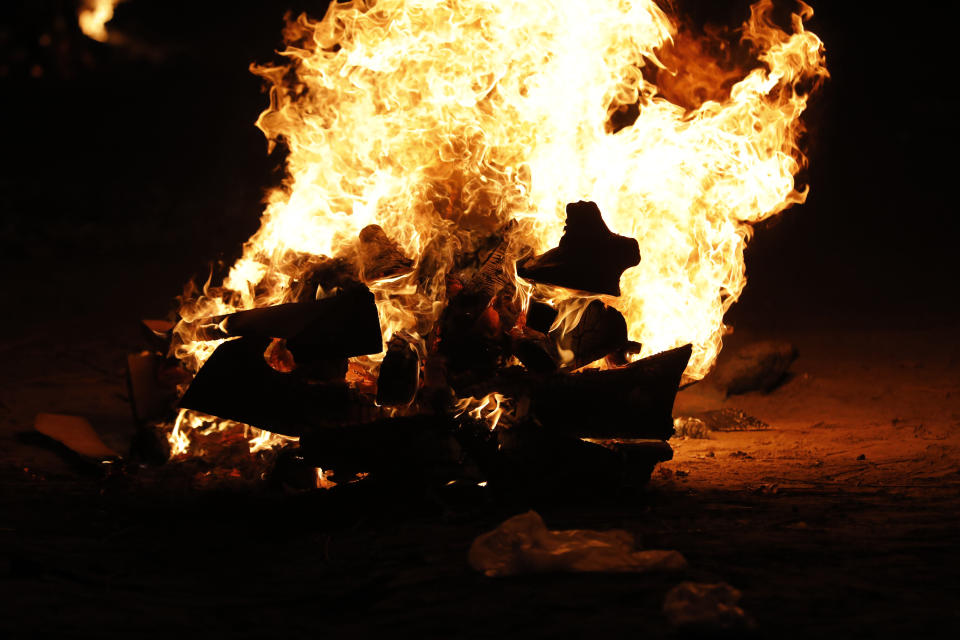 Relatives stand near the funeral pyre of their loved one who died due to COVID-19 at a cremation ground in Prayagraj, India, Saturday, May 8, 2021. (AP Photo/Rajesh Kumar Singh)