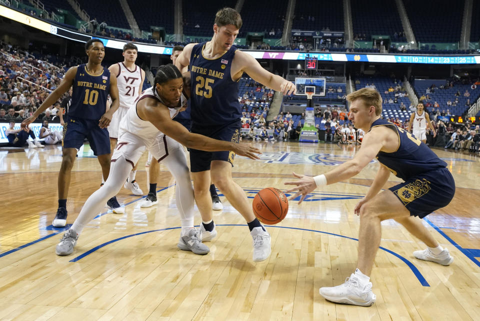 Notre Dame guard Dane Goodwin, right, and forward Matt Zona, center, stop a drive by Virginia Tech forward Mylyjael Poteat, left, during the first half of an NCAA college basketball game at the Atlantic Coast Conference men's tournament in Greensboro, N.C., Tuesday, March 7, 2023. (AP Photo/Chuck Burton)