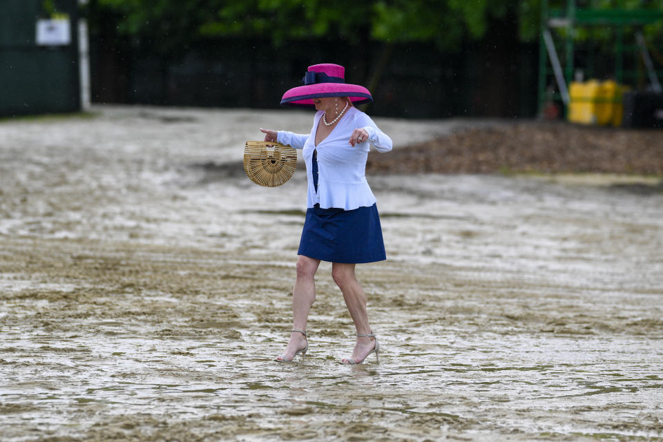 A woman walks through the mud to get to the grandstand ahead of the Preakness Stakes horse race at Pimlico Race Course, Saturday, May 18, 2024, in Baltimore. (AP Photo/Nick Wass)