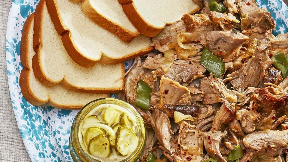 oven roasted pulled pork with sweet and spicy sauce on a serving plate with slices of bread