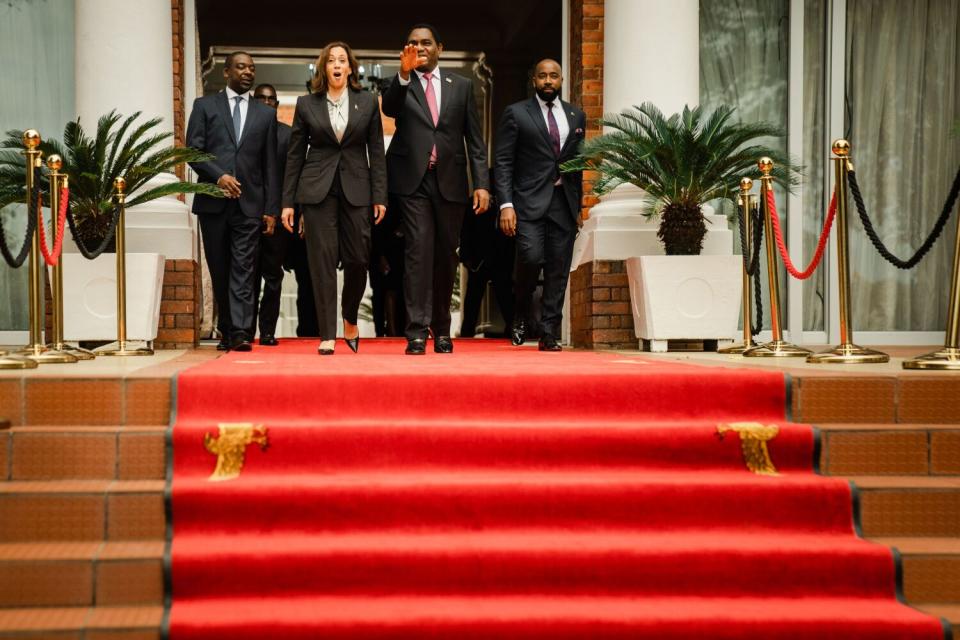 A man and woman walk together while several other people follow.