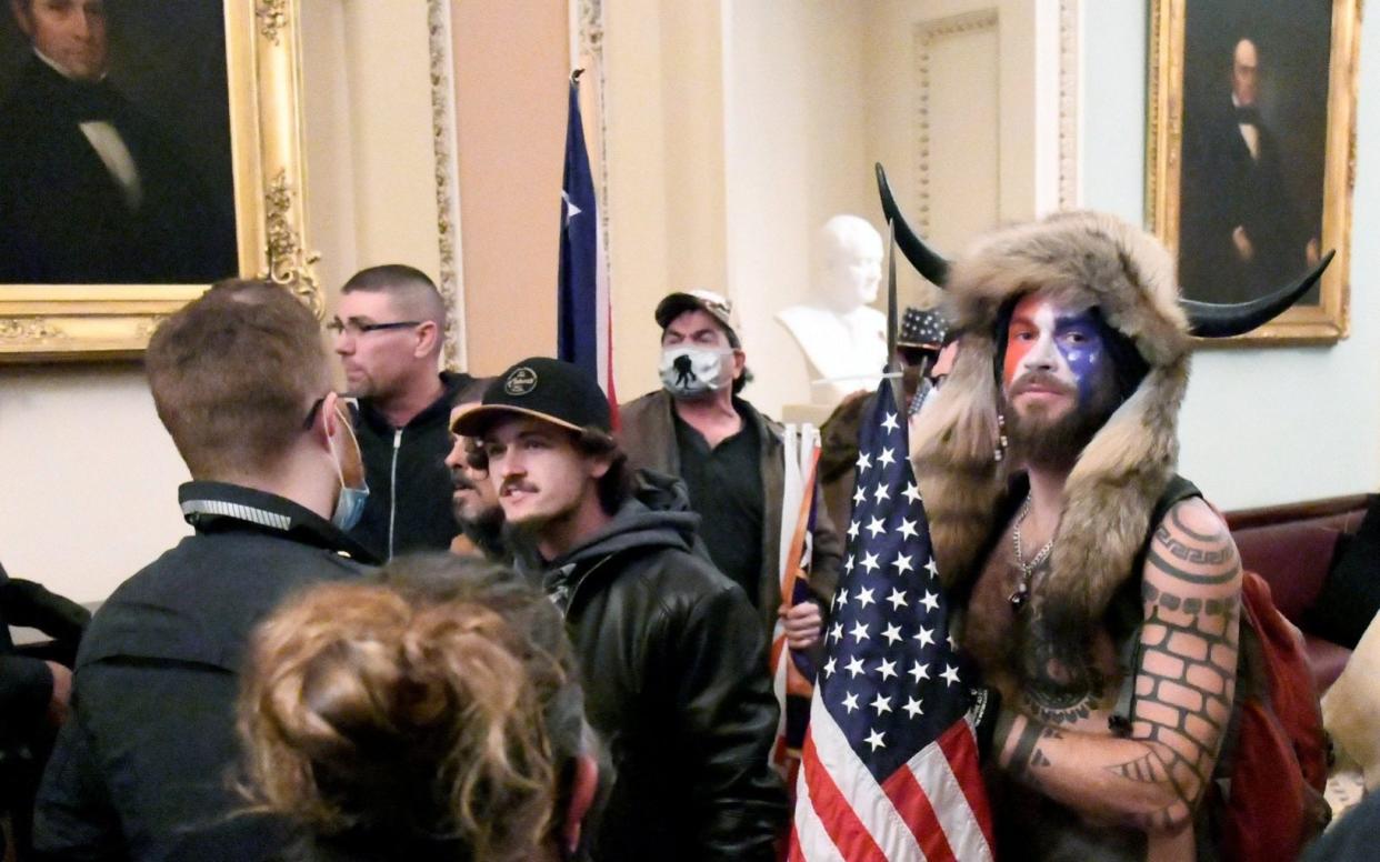 Jake Angeli (R) is seen inside the US Capitol building during the pro-Trump riots - Mike Theiler /Reuters