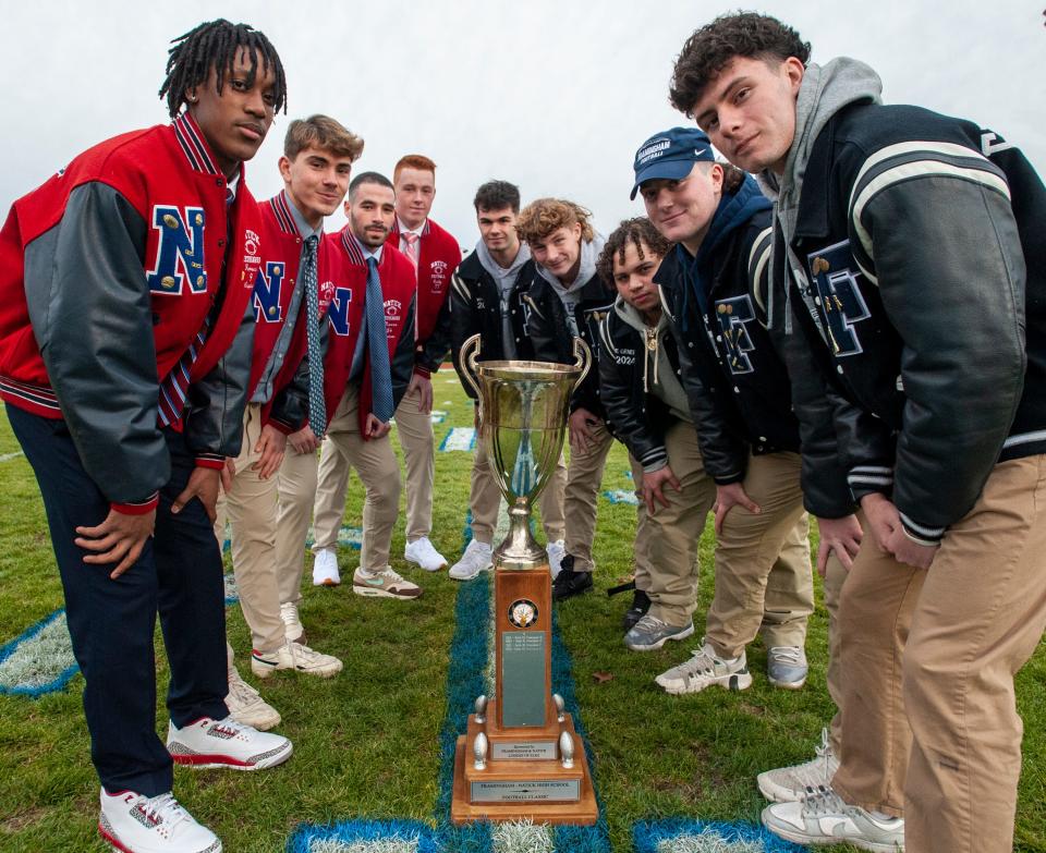 Framingham and Natick High School football captains with the Elks Trophy from left: Arnold Kawere, Teddy Ferrucci, Jared Marcus, Jack Cuddy, Caiden Whitney, Ben Lincoln, Angel Colon, Henry Goldberg and Nick Duplessis, at Bowditch Field, Nov. 21, 2023.