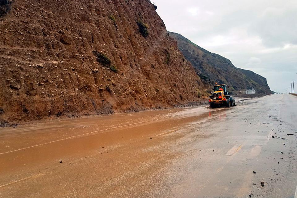 This photo provided by the California Department of Transportation (CalTrans) shows a skiploader clearing a river of mud that has flowed onto Pacific Coast Highway in Malibu, Calif., Jan. 14, 2019. The first in a series of Pacific storms is moving across Southern California, where downpours could unleash mud and debris flows from large wildfire burn scars.