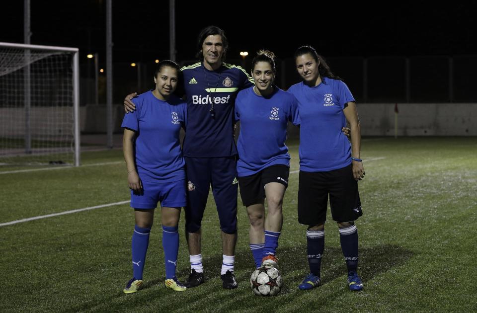 In this Tuesday, April 22, 2014 photo, from left to right, Israeli Arab players Hanin Gamal Nasser, Walaa Hussien and Noura Abu-Shanab pose with their coach during a practice session in Petah Tikva, Israel. When the Israeli women’s soccer team Hapoel Petah Tikva lost a number of its players to Israel’s national team ahead of World Cup qualifiers, founder Rafi Subra made a decision that sets the team apart from many of its rivals _ he recruited from the Arab villages of northern Israel. For Hapoel Petah Tikva, the addition of five Arab-Israeli women has made waves in the league, as Arab-Israelis often face discrimination in Israel on and off the field. (AP Photo/Tsafrir Abayov)