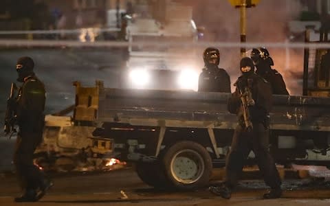 Heavilly armed police guard a crime scene during unrest in the Creggan area of Londonderry - Credit: PA