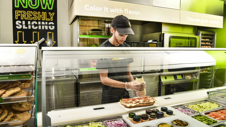 subway worker squeezing sauce