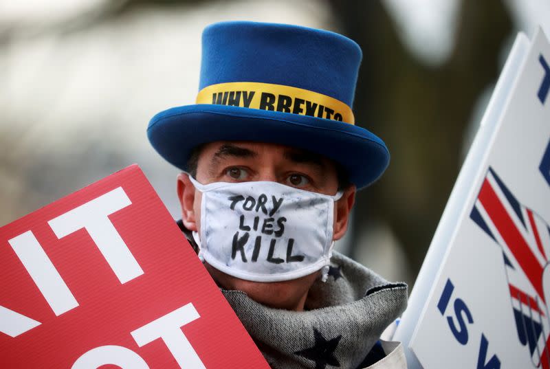 Anti-Brexit protester Steve Bray, wearing a protective mask, holds signs outside the gates of Downing Street in London