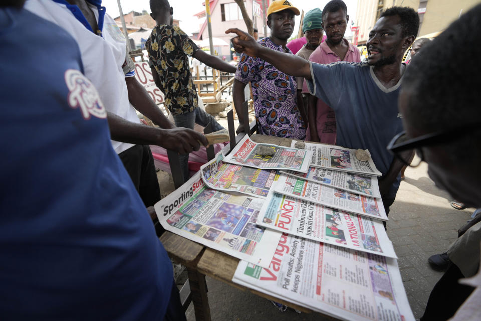 People argue as they read local newspapers with preliminary presidential election results in a street in Lagos, Nigeria, Monday, Feb. 27, 2023. Each of the three frontrunners in Nigeria's hotly contested presidential election claimed they were on the path to victory Monday, as preliminary results trickled in two days after Africa's most populous nation went to the polls. (AP Photo/Sunday Alamba)