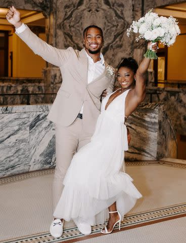 RAETAY PHOTOGRAPHY Simone Biles striking a smiling pose while holding a flower bouquet alongside husband Jonathan Owens on their wedding day in April 2023.