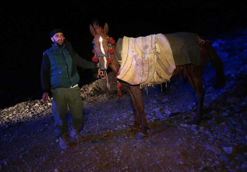 In this picture taken early Sunday, April 20, 2014, Ibrahim Abdulghani, 32, leads his horse loaded with the belongings of Syrian refugees as he descends from the 2,814-meter (9,232-foot) high Mount Hermon (Jabal el-Sheikh), in southeast Lebanon. Abdulghani, from Syria, works as a construction worker during the day in Lebanon and volunteers at night to help Syrians escape. Only the most desperate risk the perilous journey, Abdulghani said. The list of dangers, he said, runs long: crossfire from clashes; snipers; airstrikes; snow in winter and pouring rain in spring. For fear of being spotted by snipers while climbing up the mountain on the Syrian side, smoking is prohibited. “They can light up a cigarette when they descend into Lebanon,” he said.(AP Photo/Hussein Malla)