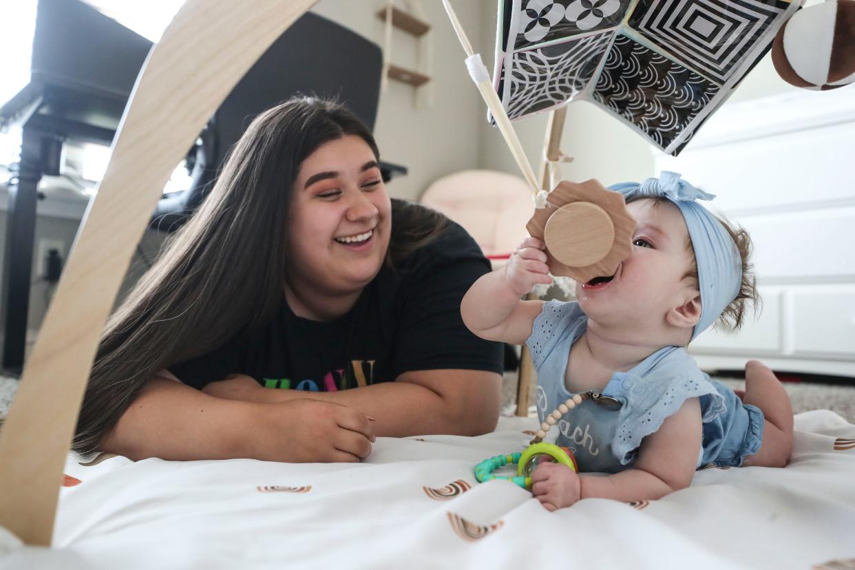 Krysten Erb smiles while her daughter Lina plays in their apartment. Erb is working to support her daughter as well as working on her GED.