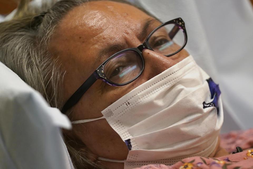 Joyce Johnson-Albert looks on as she receives an antibody infusion while lying on a bed in a trauma room at the Upper Tanana Health Center Wednesday, Sept. 22, 2021, in Tok, Alaska. Johnson-Albert was optimistic but also realistic. "I just hope the next few days I'll be getting a little better than now," Johnson-Albert told a reporter on the other side of a closed, sliding glass door to the treatment room two days after testing positive for COVID-19 and while receiving an antibody infusion. "It's just hard to say. You can go either way." (AP Photo/Rick Bowmer)