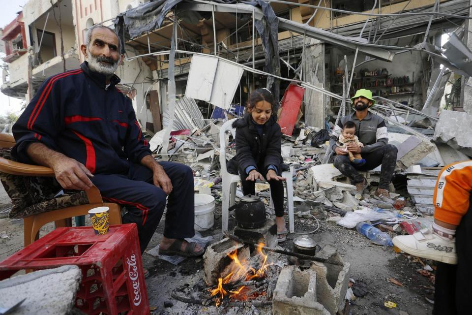 PHOTO: A family in Gaza warm themselves amid wreckage during the third day of the humanitarian pause, Nov. 26, 2023, in Khan Yunis, Gaza Strip.  (Ashraf Amra/Anadolu via Getty Images)