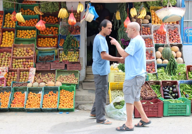 FILE PHOTO: Men chat outside a fruit shop in La Marsa near Tunis